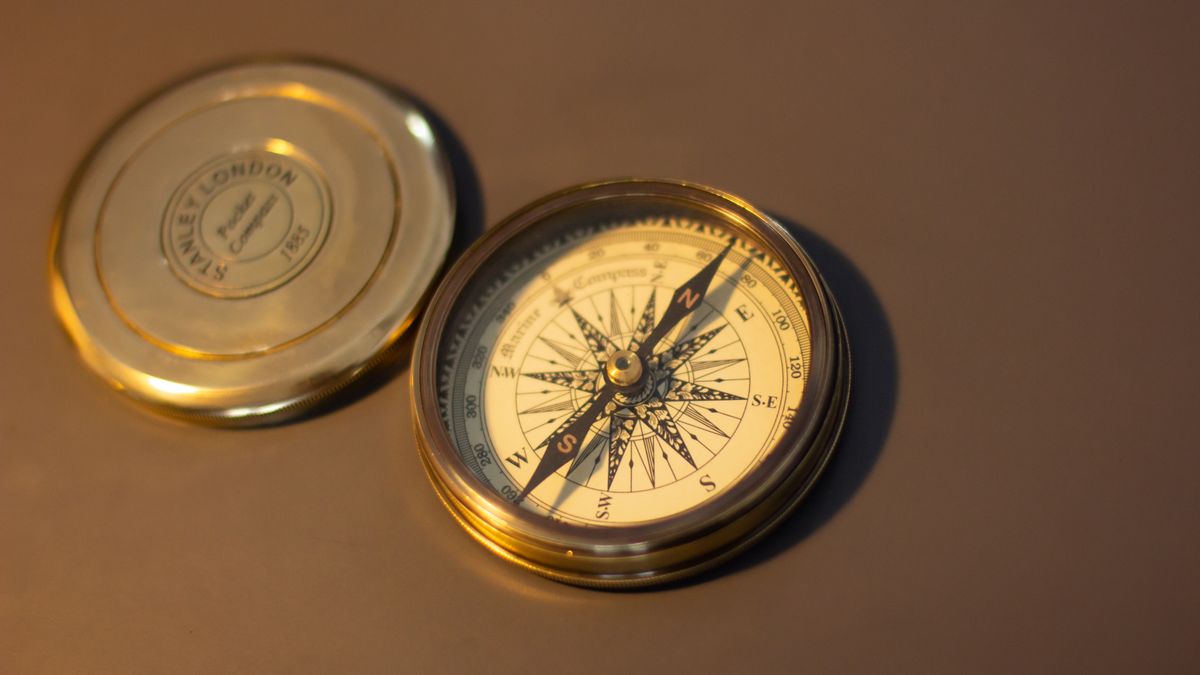 Vintage brass compass on a warm wooden surface for direction analysis